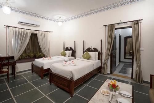 a bedroom with two beds and a table with flowers at The Amargarh in Udaipur