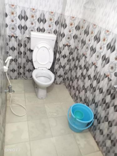 a bathroom with a toilet and a blue bucket at Rama Guest House in Bodh Gaya