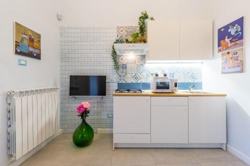 a kitchen with white cabinets and a vase with flowers at Casa Parravano in Caserta