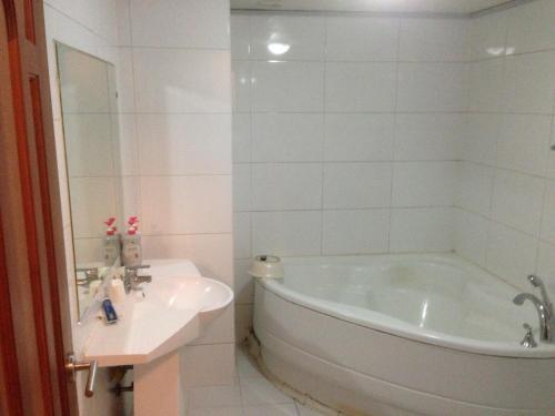 Baño blanco con bañera y lavamanos en Daegu Goodstay Herotel, en Daegu