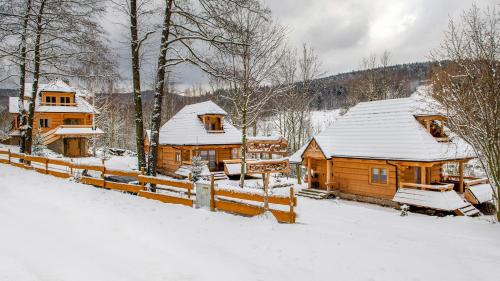 a log cabin in the snow with a fence at Osada Sudecka in Lądek-Zdrój