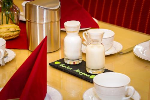un tavolo con due bottiglie di latte e tazze sopra di Wohlfühlhotel IM SCHLOSSPARK - Self CheckIn a Willebadessen