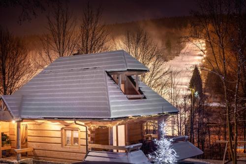 a cabin with a roof covered in snow at night at Osada Sudecka in Lądek-Zdrój