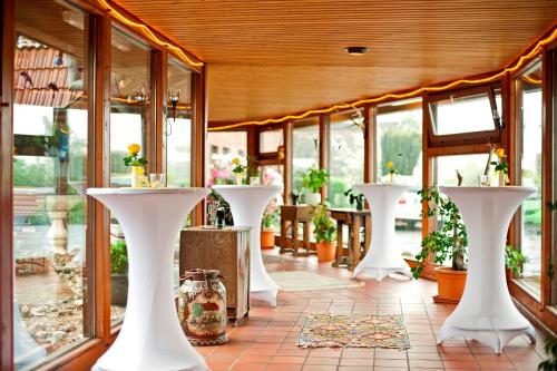 a room with white tables with potted plants at Akzent Hotel Cordes & Restaurant am Rosengarten in Sottorf