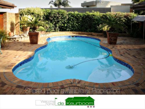 a swimming pool in a backyard with a brick patio at De Keurboom Guesthouse in Kuilsrivier