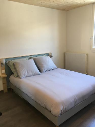 a bed with white sheets and pillows in a room at Studio des Eterlous in Saint-Chaffrey