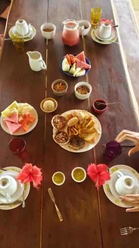 Una mesa de madera con platos de comida encima. en Casinha Amarela EcoLodge Boipeba, en Isla de Boipeba