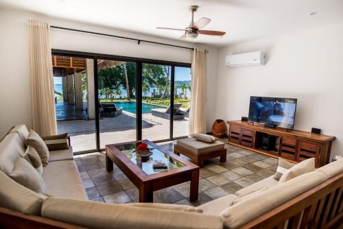 a living room with a couch and a tv at Home The Residence in Befotaka Bay