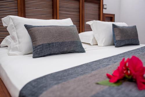 a bed with pillows and a red flower on it at Home The Residence in Befotaka Bay