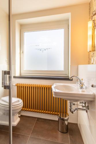 a bathroom with a toilet and a sink and a window at Nordhäuser Fürstenhof & TinySky-Resort in Nordhausen