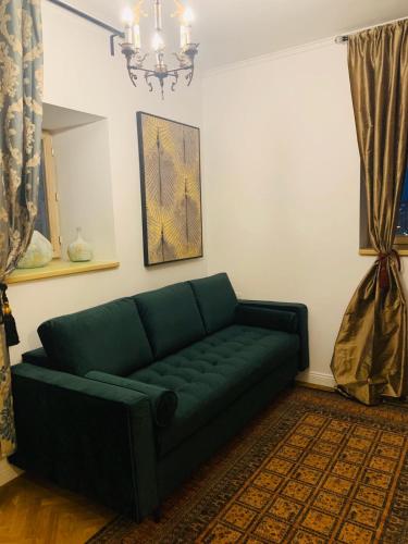 a green couch in a living room with a chandelier at Rezident in Bucharest