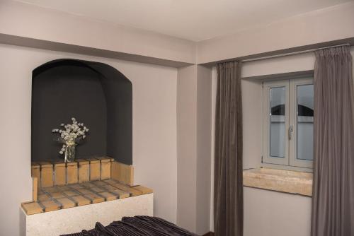 a room with a bed and a window with a vase of flowers at Boutique Rooms Mirabilis in Skradin