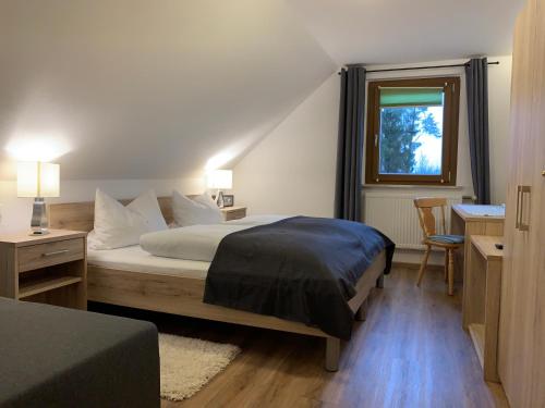 a bedroom with a bed and a desk and a window at Hohe Tanne in Aurbach