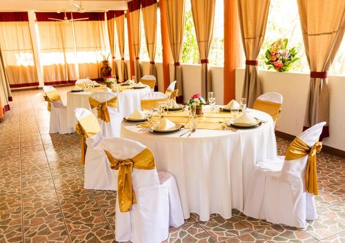 a dining room with white tables and yellow bows at Mansión Los Guichos in Retalhuleu