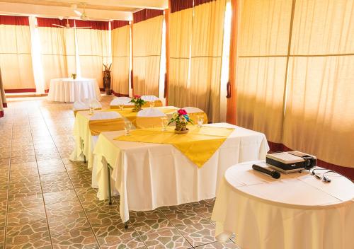 a room with two tables with white table cloths at Mansión Los Guichos in Retalhuleu