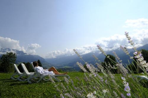 a woman sitting on a bench in the grass at Veronza Clubresidence in Cavalese