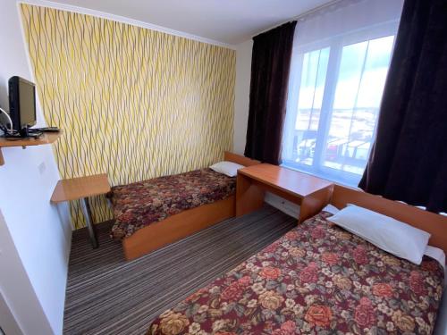 a hotel room with two beds and a desk and a window at Autopark Hotel in Lviv