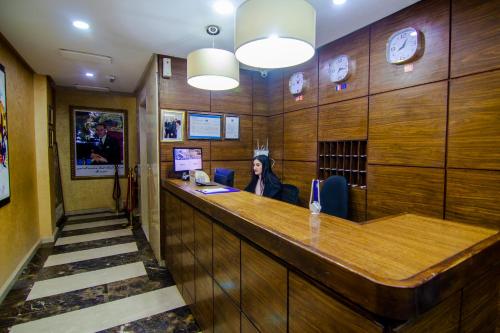 Una mujer sentada en un bar en una habitación con madera. en Hotel vallee ziz, en Er Rachidia