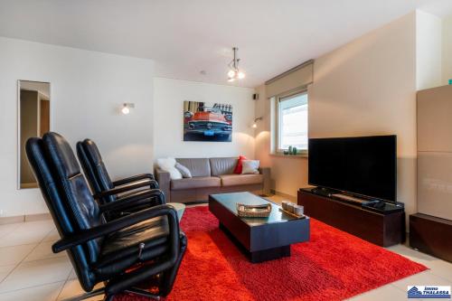 a living room with two black chairs and a flat screen tv at Amena 0101 + garage in Koksijde