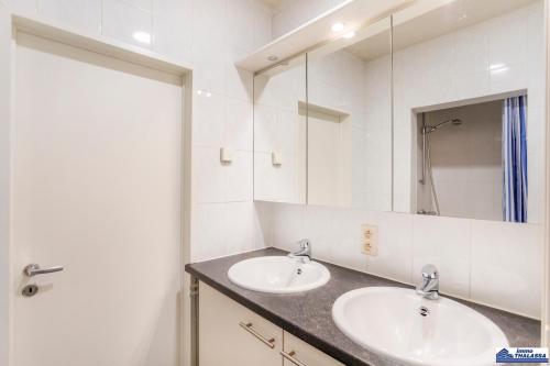 La salle de bains est pourvue de 2 lavabos et d'un grand miroir. dans l'établissement Opale 0101, à Coxyde