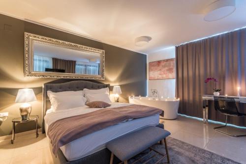 a bedroom with a large bed with a mirror and a tub at Plitvice Falls Cottage in Plitvica selo