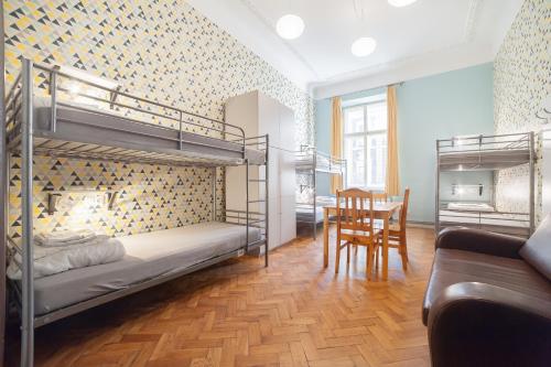 a bedroom with bunk beds and a dining room with a table at Dizzy Daisy Hostel in Kraków