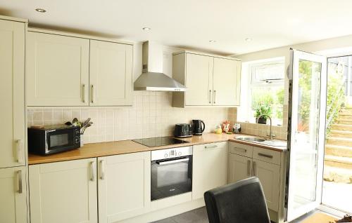a kitchen with white cabinets and a microwave at Beautiful Beach Front Cottage in Llandudno
