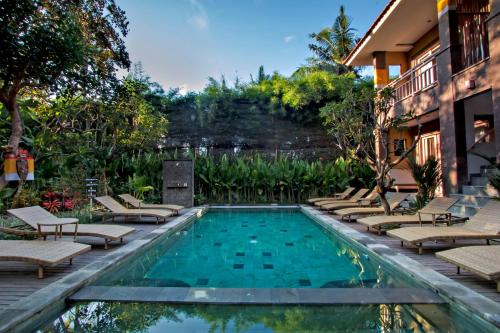 een zwembad met ligstoelen en een resort bij Ubad Retreat in Ubud