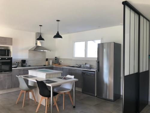 une cuisine avec une table et un réfrigérateur en acier inoxydable dans l'établissement Villa MaLou, à Pradons