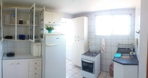 uma cozinha branca com um fogão e uma janela em Estiloso 2 Quartos Wifi e SmarTV em Guarapari