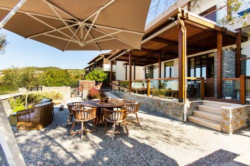 a patio with a table and chairs and an umbrella at Ayia Marina Suites in Ouranoupoli