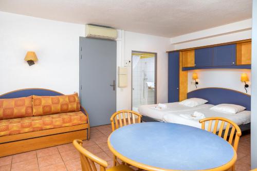 a room with two beds and a table and a couch at SOWELL RESIDENCES Chênes Verts in Saint-Raphaël