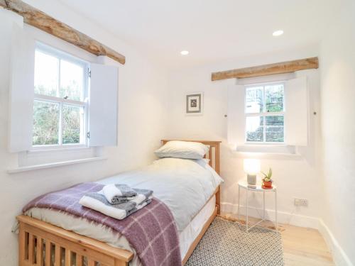 Un dormitorio con una cama y dos ventanas. en 1 Jubilee Cottage, en Tintagel