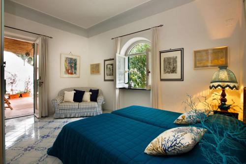 a bedroom with a blue bed and a window at Villa Le Terrazze di Capri in Capri