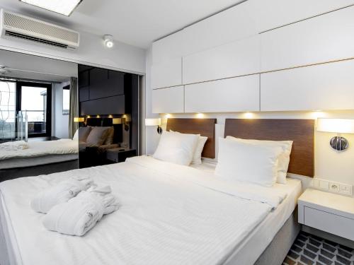 1 dormitorio con 1 cama blanca grande y toallas. en VacationClub – Marine Hotel Apartament 621 en Kołobrzeg
