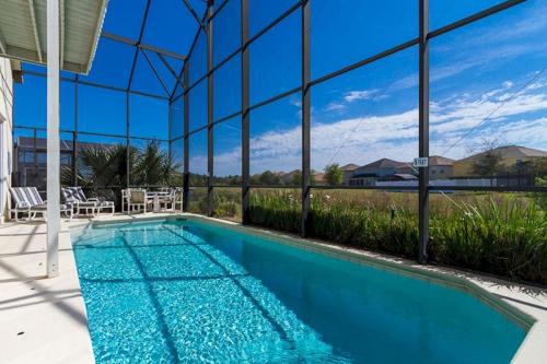 a swimming pool in a house with a glass wall at A wonderful choice for a family Vacation, 4 bedrooms and it own pool in Orlando