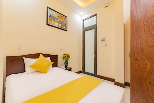 a bedroom with a bed with a yellow blanket at Green Hill Hotel in Hoi An