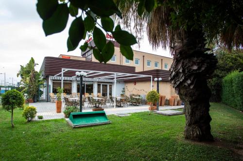 un edificio con piscina en un patio con un árbol en Ibis Valencia Alfafar en Alfafar