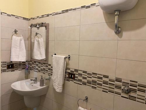 a bathroom with a sink and a mirror and towels at Guest House Brandino Pani in Tertenìa