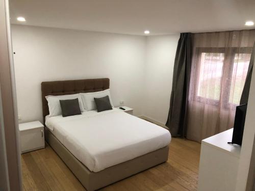 1 dormitorio con cama blanca y ventana en Pensiunea Exedra en Borşa