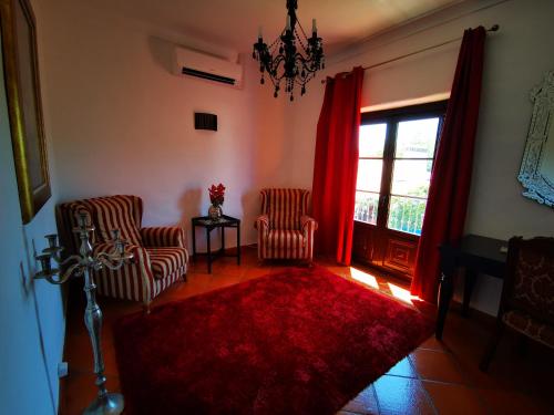 a living room with two chairs and a red rug at Monte Alerta Turismo Rural in Monsaraz