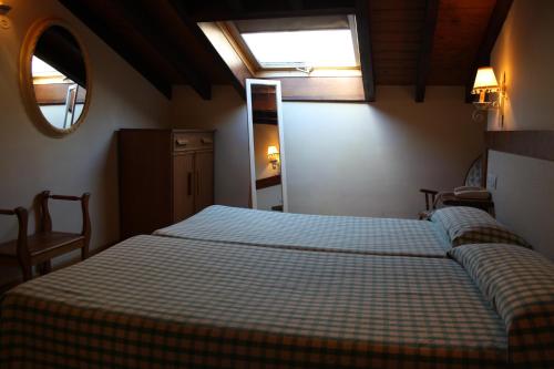 a bedroom with a bed with a checkered blanket and a window at Hostería La Antigua in Potes