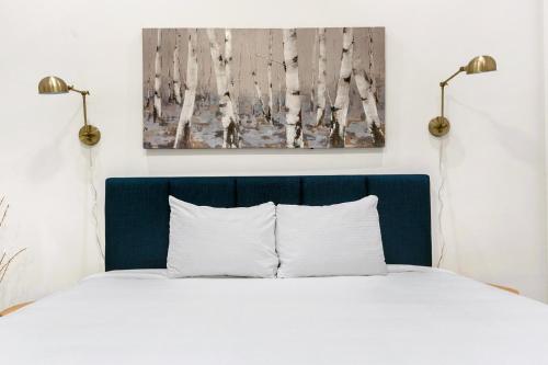 a bed with white pillows and two lights above it at 1 and 2 BR Private Condos Steps Away From French Quarter in New Orleans