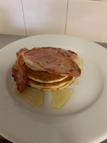 Khyber Mount Guest House في ويتبي: كومة من الفطائر مع لحم الخنزير المقدد وشراب القيقب على طبق