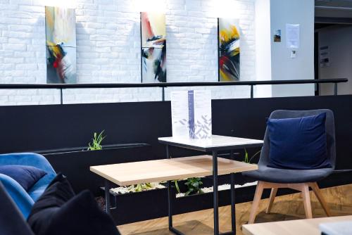a table and two chairs in a room with paintings at Mercure Lorient Centre in Lorient