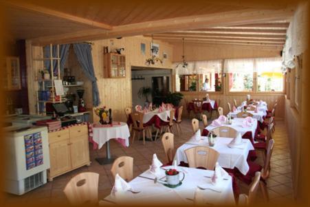 um restaurante com mesas e cadeiras brancas e uma cozinha em Gasthof zum Schlern em Fiè
