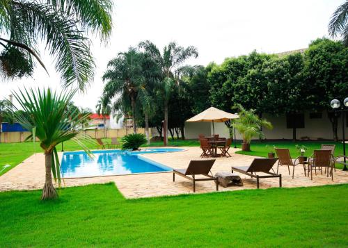 a pool with chairs and a table and an umbrella at Terras Hotel in Lucas do Rio Verde