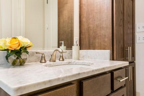 a bathroom with a sink and a vase of yellow roses at 1 and 2 BR Private Condos Steps Away From French Quarter in New Orleans