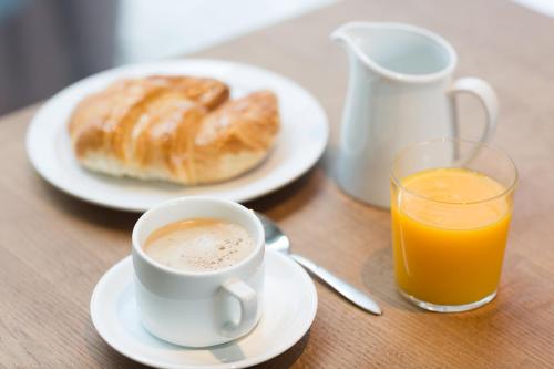 a table with a cup of coffee and a plate of orange juice at Urban A+++ Hotel in Tres Cantos
