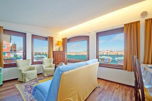 ein Wohnzimmer mit einem blauen Sofa und Fenstern in der Unterkunft DolceVita Apartments N 453 Canal View in Venedig